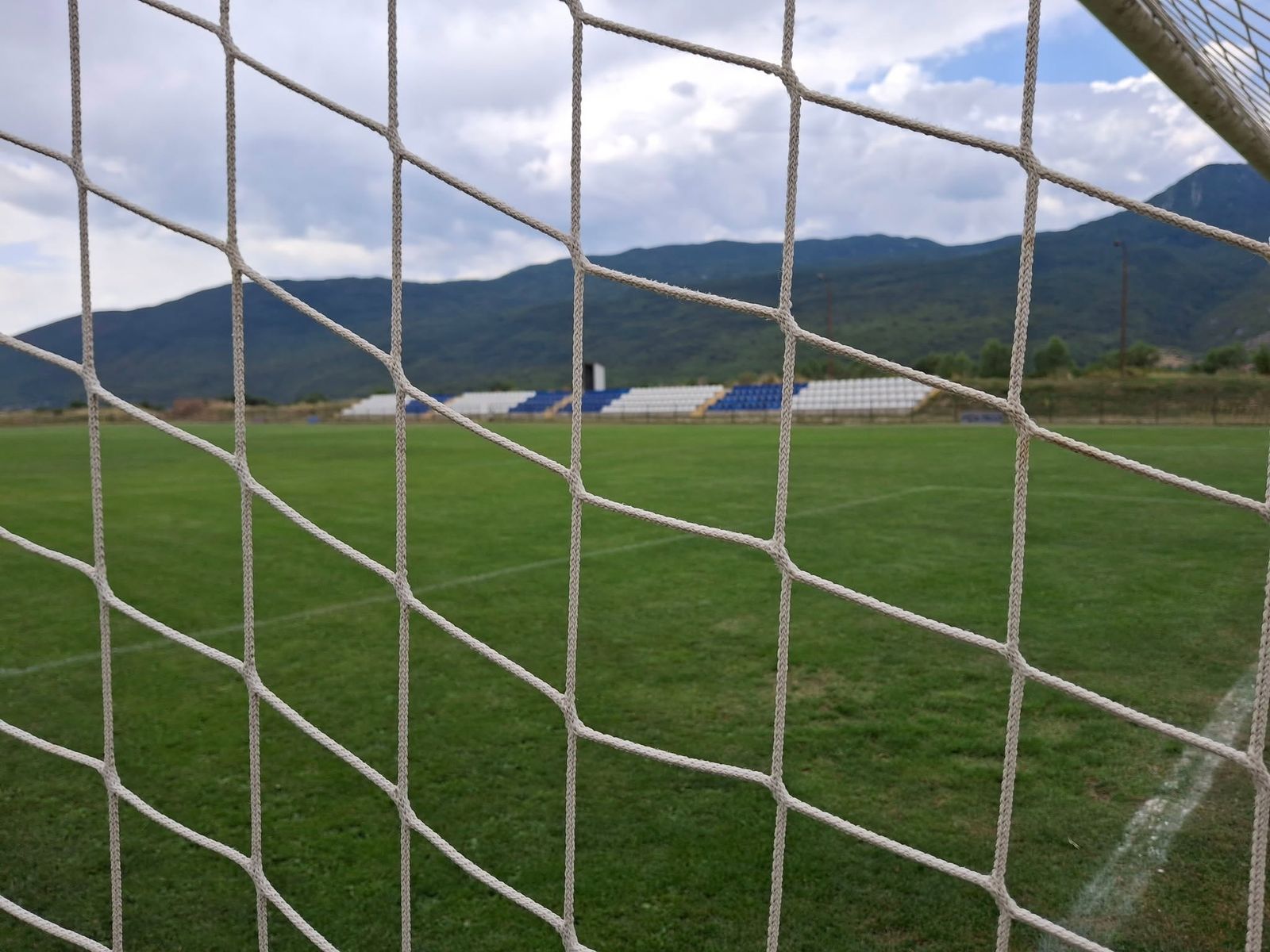 Rasenplatz von NK Kamešnica mit Tribüne und Bergen im Hintergrund
